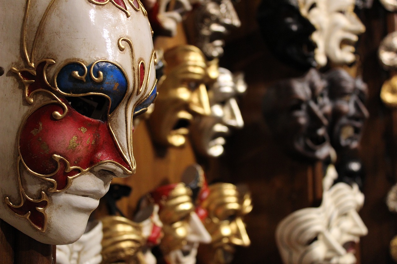 A masked figure standing ominously next to a wall of theater masks.