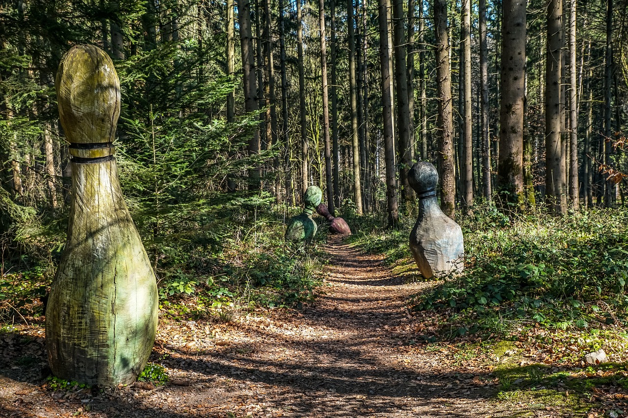 Giant bowling pins at different distances down a forest trail.