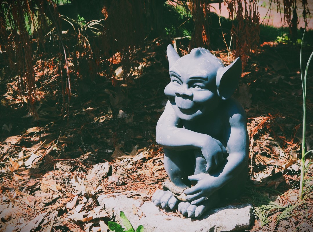 A statue of a goblin with a sneaky grin.