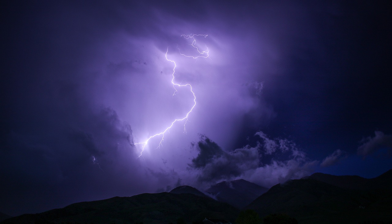 A bolt of lightning strikes dramatically over a dark mountain.